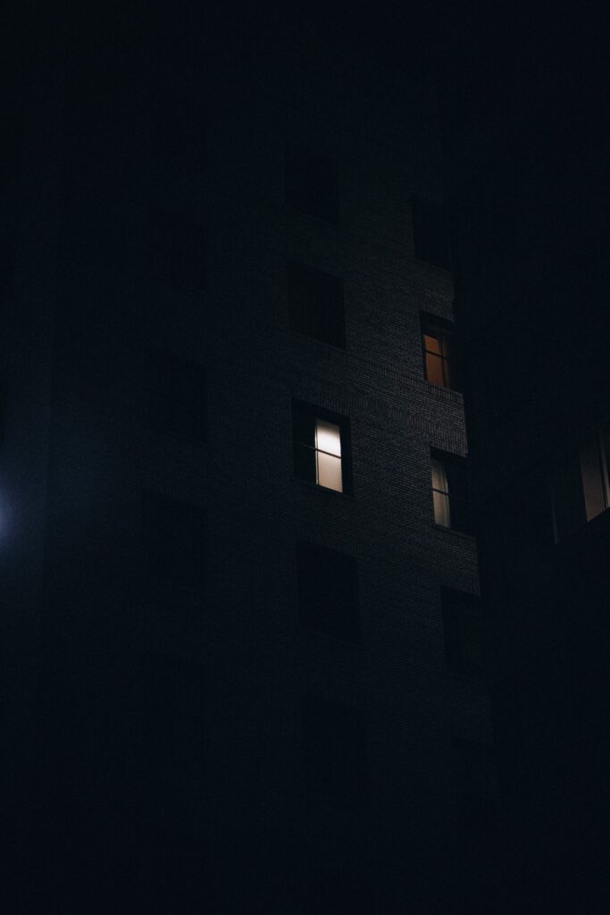 Dimly lit building at night with a few illuminated windows