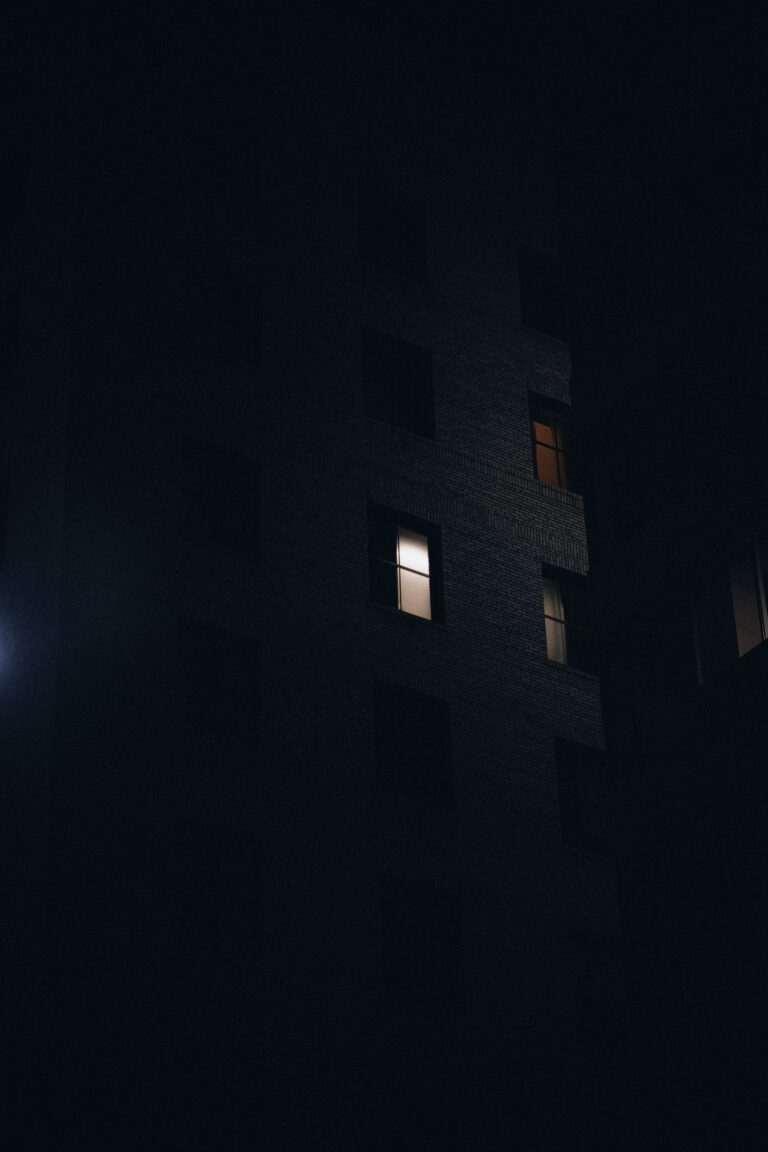 Dimly lit building at night with a few illuminated windows